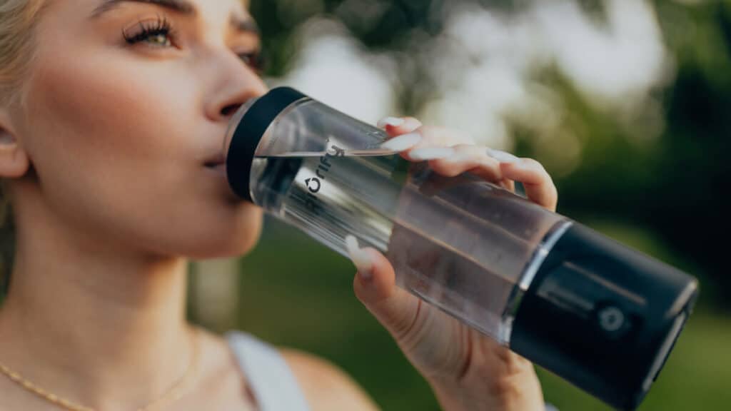 A girl drinking water from a glass bottle