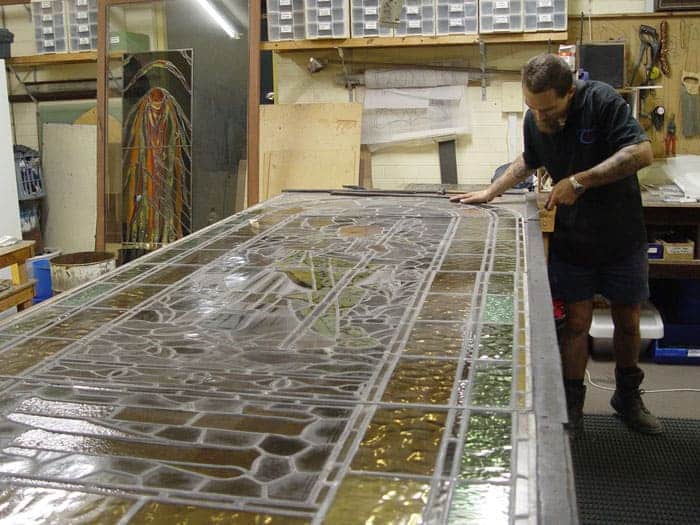 A guy assessing a broken stained glass