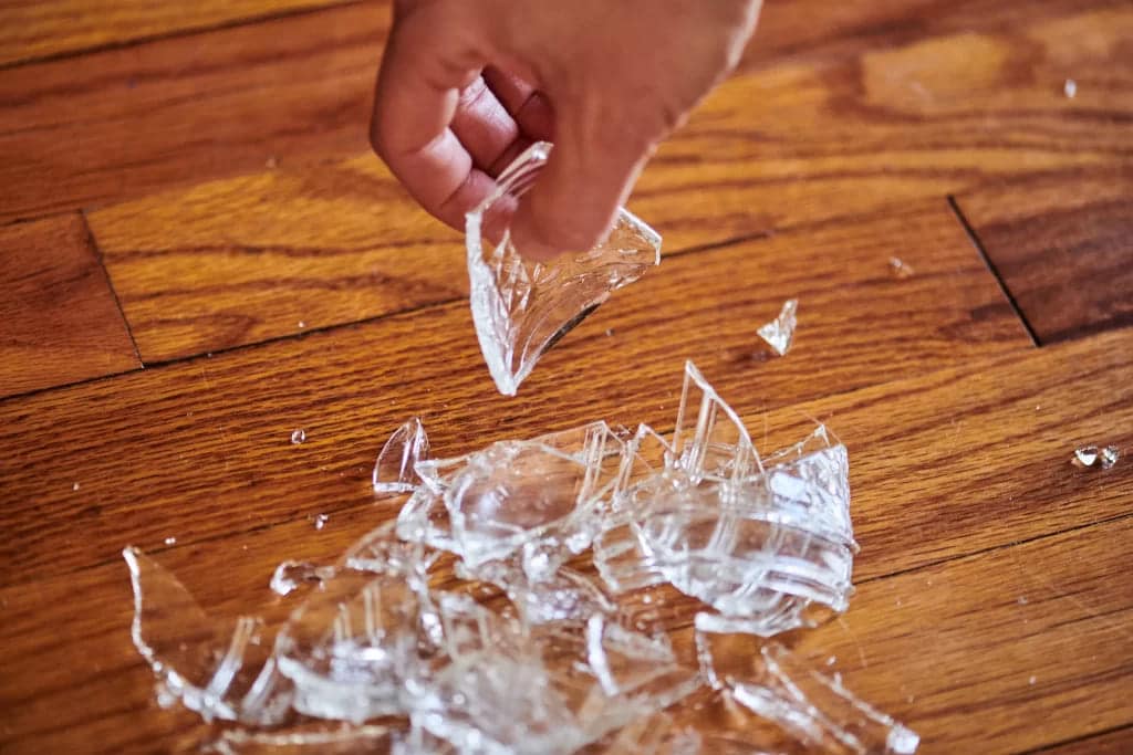 A hand picking broken glass pieces