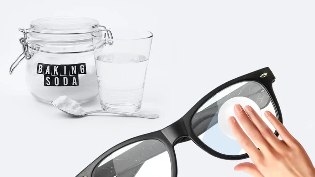 A hand wiping off glasses along with a water anbd baking soda in a spoon