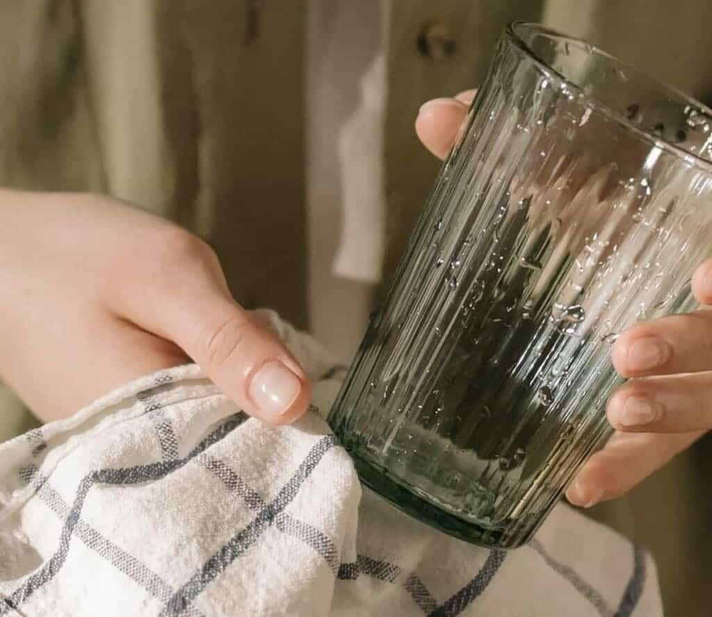 A person cleaning a wet glass with cloth