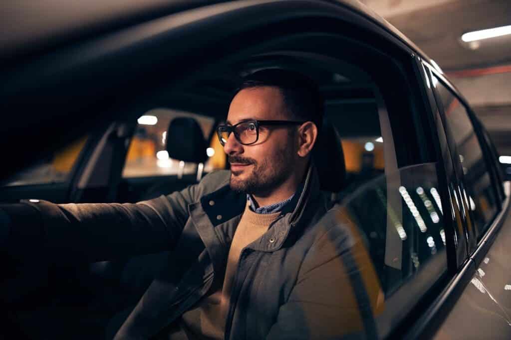 A person driving car wearing glasses in the night