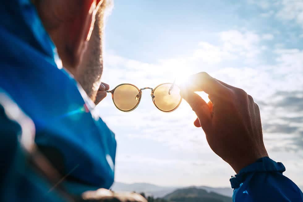 A person holding up glasses and looking at the sun through them