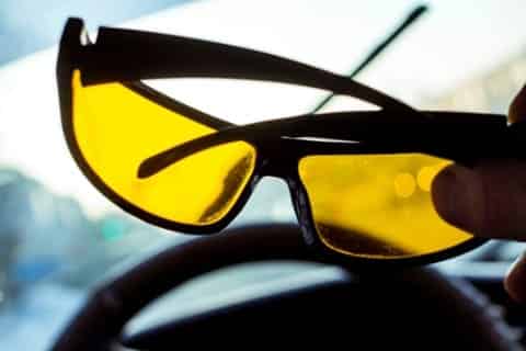 A person holding yellow tinted glasses