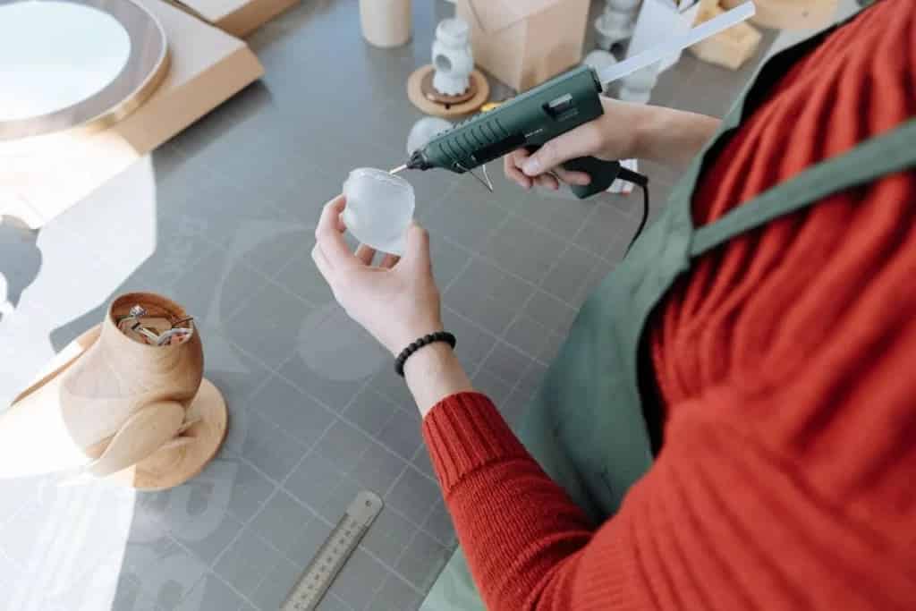 A person putting glue on glass with a glue gun