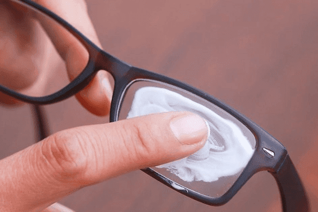 A person putting white solution on the glasses for repair