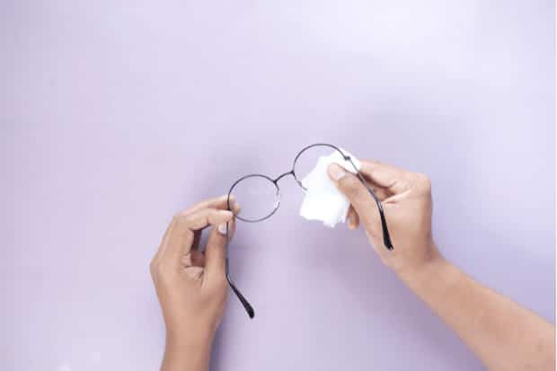 A person removing glue off glasses with a cloth