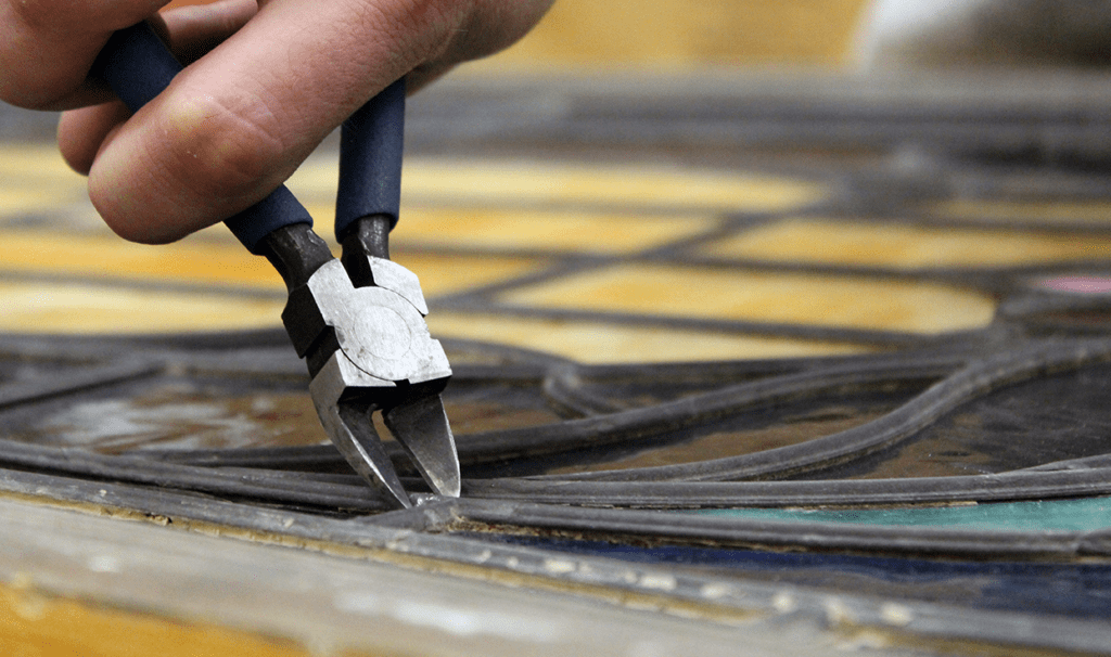 A person repairing a stained broken glass with a plier tool