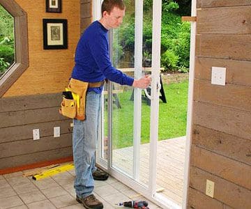 A person standing and finalizing the installation of a sliding glass door