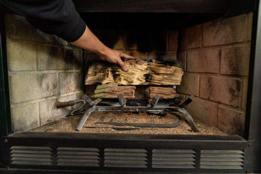 A person touching the fireplace wood