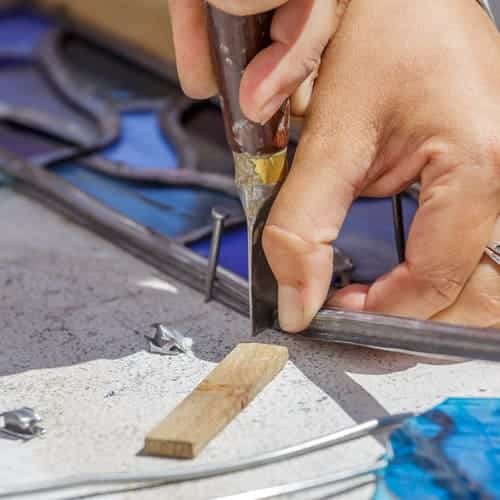 A person using tools to cut stained glass 