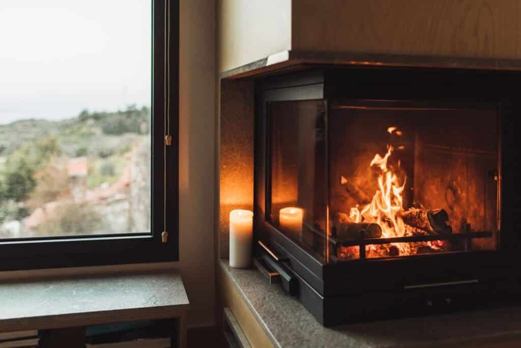 A view of a brightly lit fireplace next to a glass window