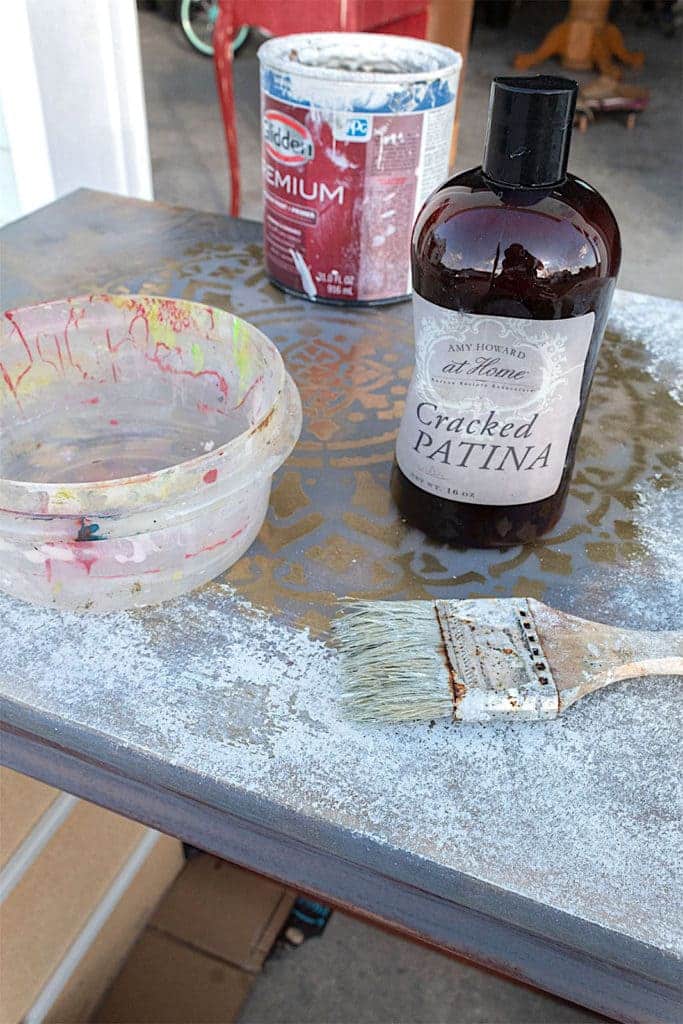 A view of cracked patina dresser alongside a paintbrush and a paint bucket