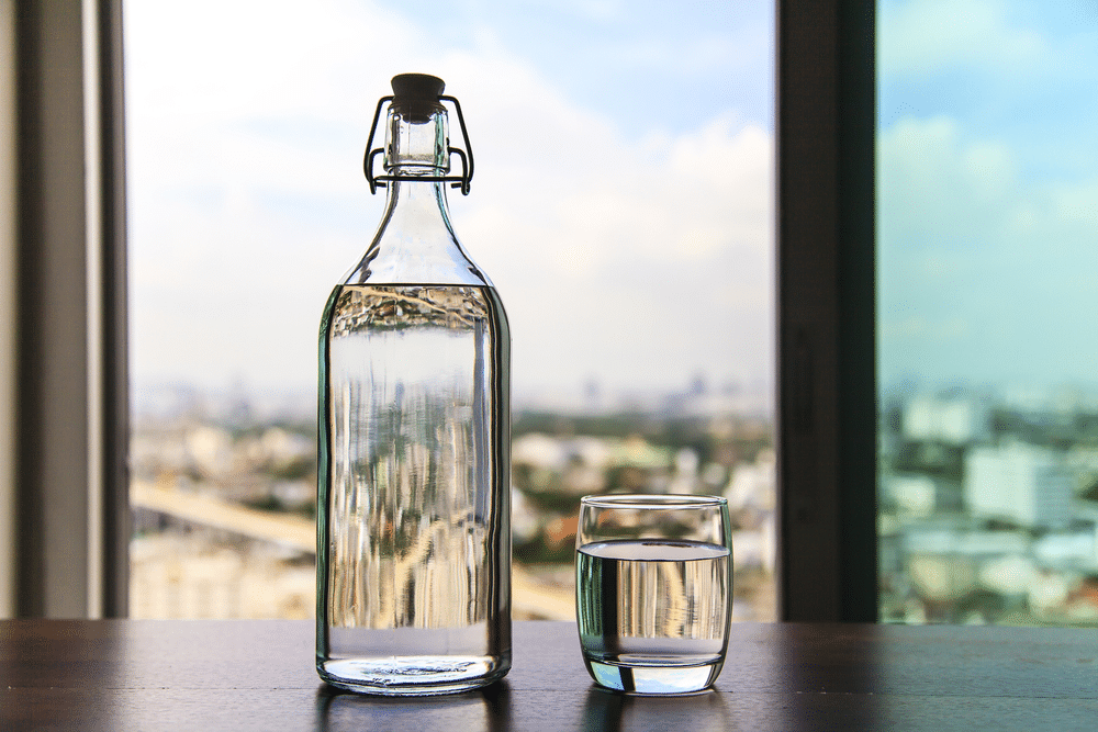 Glass of water with a bottle on table