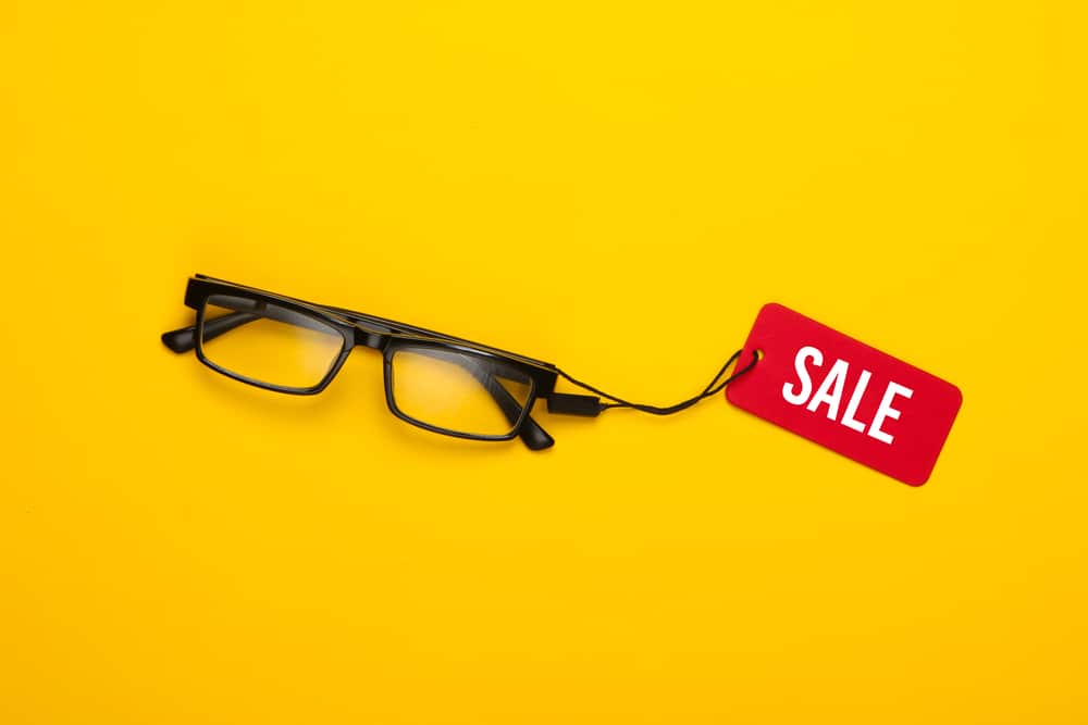 Glasses With Red Sale Tag On Yellow Background Top View