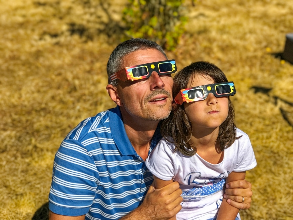 Father And Daughter Family Viewing Solar Eclipse With Special Glasses