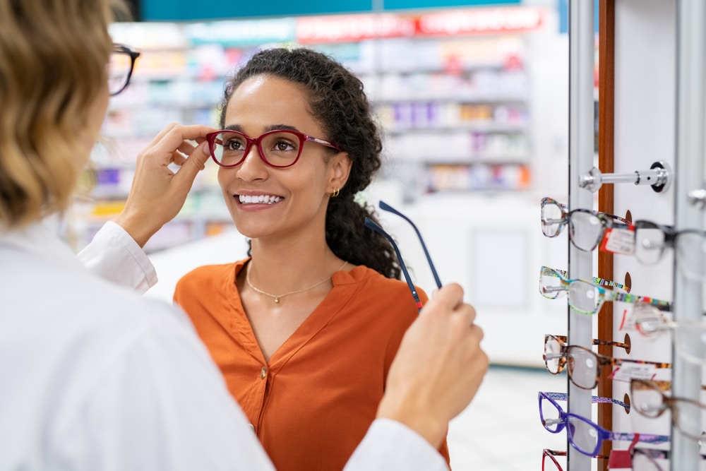 African young woman in optic store choosing new glasses