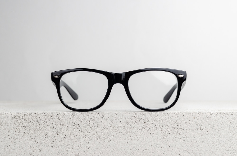 Elegant black wayfarer glasses placed on a white brick with blank background color. 