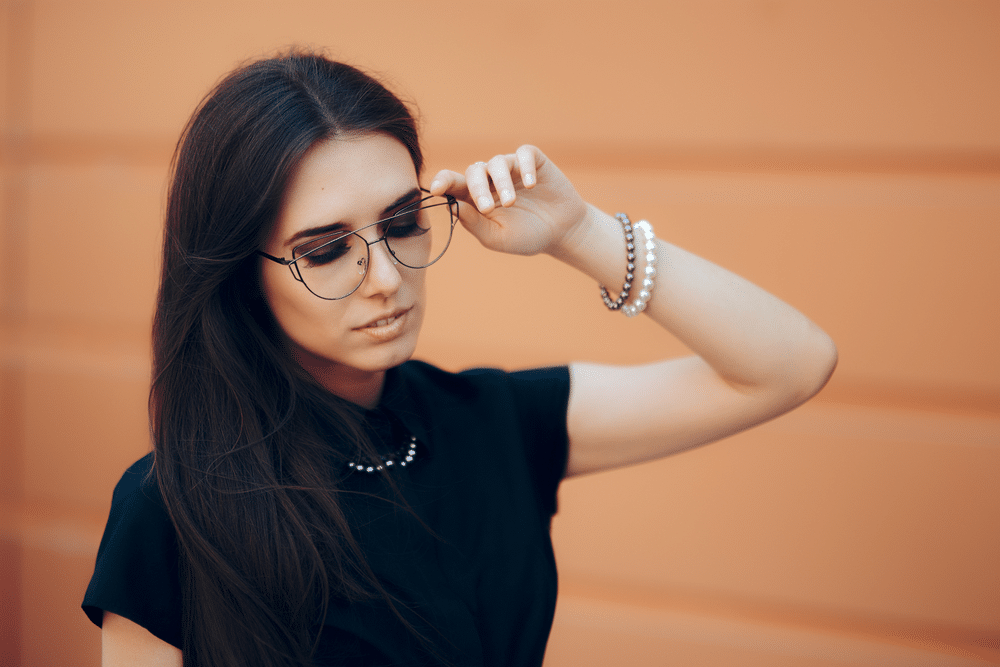 a girl in black dress wearing oversized frames