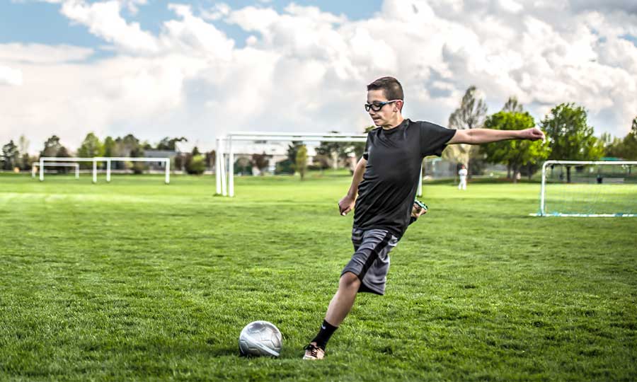 A view of a boy kicking a ball in ground A view of a boy kicking a ball in ground