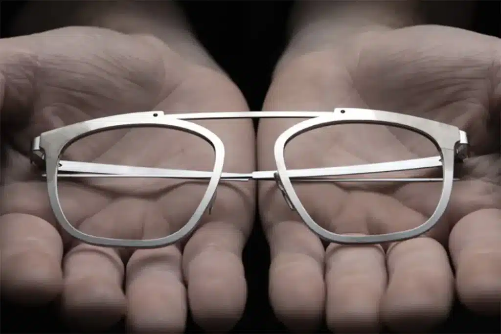 A close up image of metal eyeglass frames being held in two hands showcasing a sleek minimalist design A close up image of metal eyeglass frames being held in two hands showcasing a sleek minimalist design