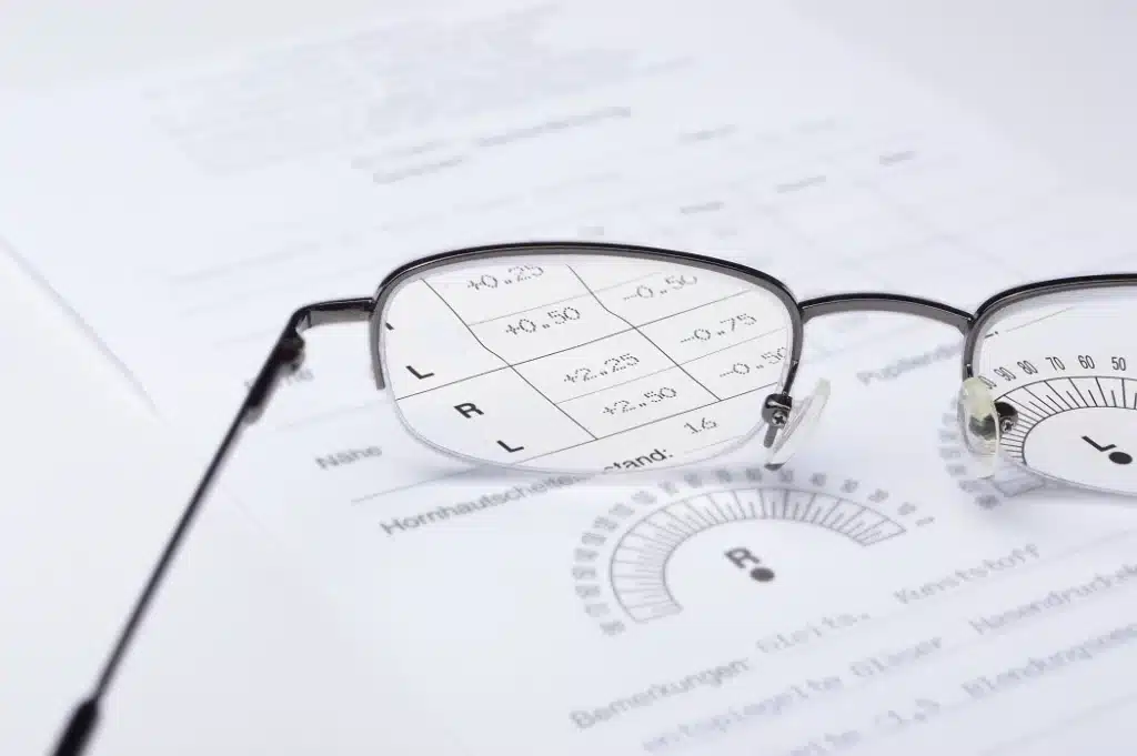 A close up of eyeglasses resting on an eyeglass prescription form showing measurements for both eyes A close up of eyeglasses resting on an eyeglass prescription form showing measurements for both eyes