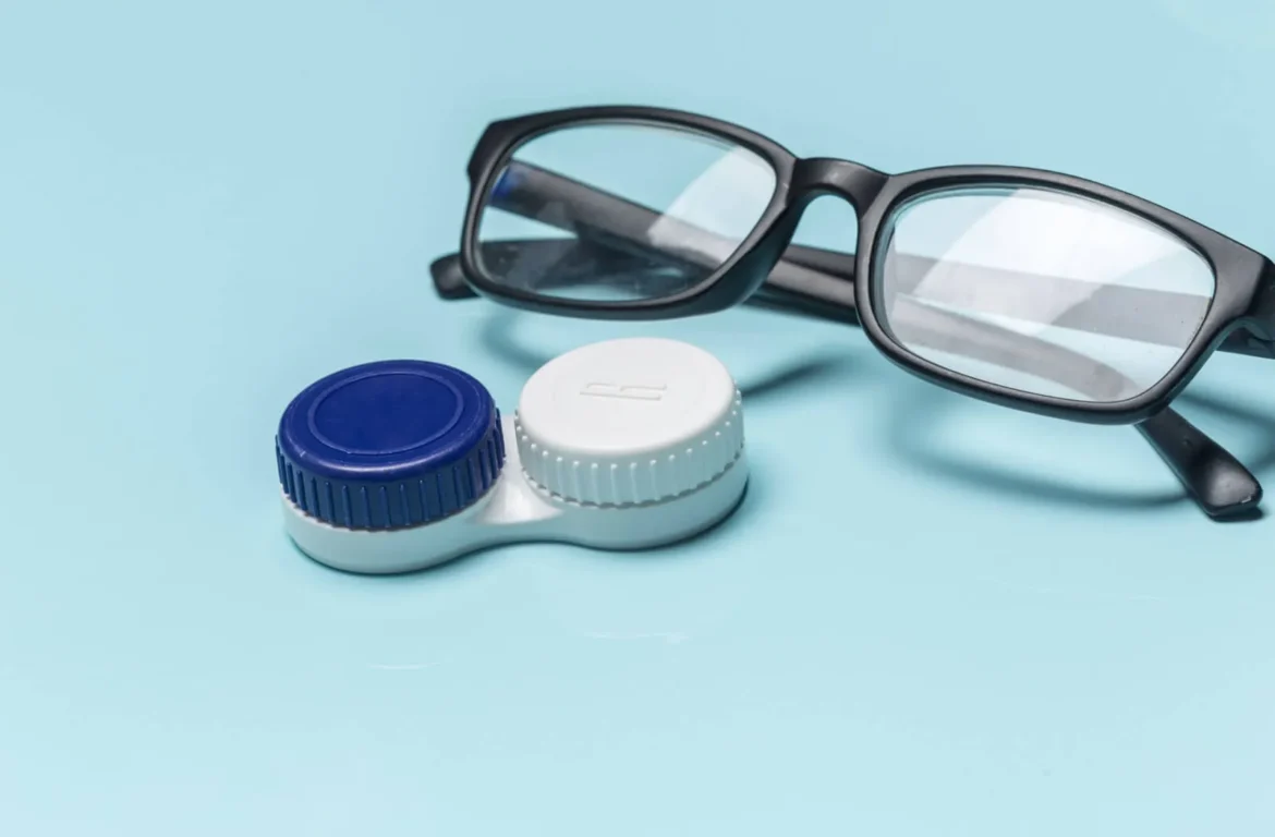 A pair of eyeglasses next to a contact lens case on a blue background
